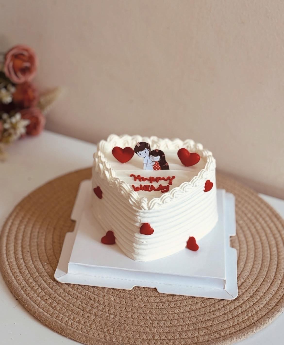 Heart-shaped birthday cake with custom couple illustration